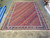 10'4" x 14'2" Indian Soumak rug shown flat on warehouse tile floor