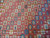 Close field photograph of all-over tribal motifs in gold, indigo, black and coral wool