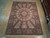 Full view of the 9x12 ivory dome design rug laid flat on showroom wood flooring