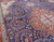 Detail of navy field paisley boteh vines curling around the salmon medallion on hand-knotted wool