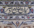 Woven signature cartouche in navy script set into the ivory guard border of the rug