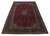 Angled floor shot of oversize red Kashan rug showing navy border and ivory corner spandrels