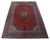 Oversize red and blue Kashan rug shown at an angle with ivory spandrels and floral borders