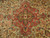 Close-up of olive gold medallion centered in coral cartouche surrounded by ivory floral vinework