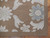 Corner detail showing the plain brown border band, flat tapestry weave and blue grey flower