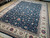 9x12 hand-knotted rug angled on wood floor, dense vine scroll across deep navy field