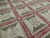 Close angled detail of ivory rosettes, olive corner triangles and laurel sprigs on raspberry dividing bands