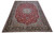 Angled full view of oversize 11x16 Isfahan rug showing red field and indigo main border