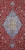 Detail of pastel blue stepped medallion, ivory center rosette and dense red floral vine field