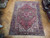 Semi-antique Heriz wool rug photographed on parquet floor showing red field and deep navy main border