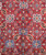 Close-up of rose, navy and sky blue rosettes with boteh paisley on tomato red wool