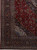 Corner detail showing ivory spandrel, navy main border and dense floral vinework on maroon ground