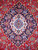 Close-up of ivory and light blue lobed medallion set into navy on crimson Kashan field