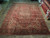 9'8" x 12'10" Heriz rug photographed at an angle showing navy border and red floral field
