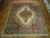 Ivory and teal floral Persian rug photographed on parquet floor showing open field and scalloped border