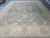 Oversize 13' x 17'8" Peshawar rug angled on showroom floor showing sage field and wide beige border