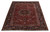 Angled floor view of red and black Heriz wool rug showing palmette border and ivory scrollwork