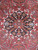 Close-up of stepped black medallion with sky blue and camel rosettes on brick red ground
