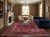 Formal living room with blue velvet sofa, fireplace and red Heriz rug under glass coffee table
