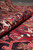 Rolled edge revealing plush wool pile depth and saturated red, navy and gold coloring