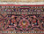 Close-up of the woven signature cartouche set into the navy border of this signed rug