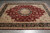 Overhead view of wine red hand-knotted rug with sage spandrels and deep black main border