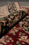 Rolled edge of the burgundy wool and silk rug showing pile depth and black border