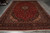 Hand-knotted Kashan wool rug laid flat showing ivory fringe, navy border and dense floral field