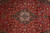 Close-up of the navy lobed medallion, ivory cartouche and scrolling vine work on red ground