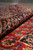 Rolled navy main border resting on the red floral field, showing pile depth and color