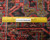 Back of the rug beside a ruler confirming hand-knotted wool construction and knot density