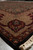 Angled view along the border showing crown palmette motif, rust accents and thick wool pile
