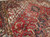 Brick red field with olive green leaves and ivory spandrel detail, hand-knotted wool pile