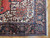 Corner detail of ivory spandrel, navy palmette border and cotton fringe on hand-knotted wool pile