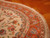Curved edge and ivory fringe of the wool and silk oval Persian rug on parquet