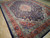 Angled view of hand-knotted Kashan rug, terracotta orange border and dense navy floral field