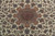 Close view of the lobed rose-brown medallion set among scrolling vines and palmettes on ivory