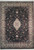 Full overhead view of black Tabriz design Oriental rug with ivory medallion and floral border
