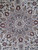 Close-up of central medallion with navy palmettes, burgundy rosettes and olive leaves on ivory wool pile