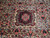 Close-up of burgundy floral medallion surrounded by pink roses on cream Persian Bijar field