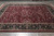 Burgundy all-over floral field and near-black border shown on grey tile showroom floor