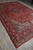 Angled floor view showing the 10x15 rug's deep red field, navy medallion and cream spandrels