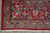 Corner of the red rug with floral main border, blue guard bands and ivory fringe