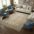 Beige Kashan rug styled in a living room with cream sofa and blue armchairs
