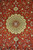 Close-up of the ivory and gold rosette medallion set on a deep red silk field