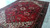10x13 Persian village rug photographed on concrete floor, red field with ivory corner spandrels visible
