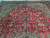Oversize 10x16 Persian rug photographed at an angle showing red field, ivory spandrels and navy border
