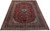 Angled floor view showing deep red Kashan rug with navy border and ivory corner spandrels