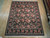 8'1" x 10' hand-knotted Oriental rug displayed on light wood showroom floor with fringed ends