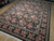 8x10 black floral Oriental rug photographed at an angle, showing rose bouquets across wide borders